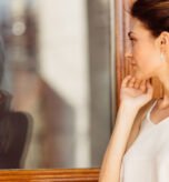 Attractive woman looking her reflection in the window